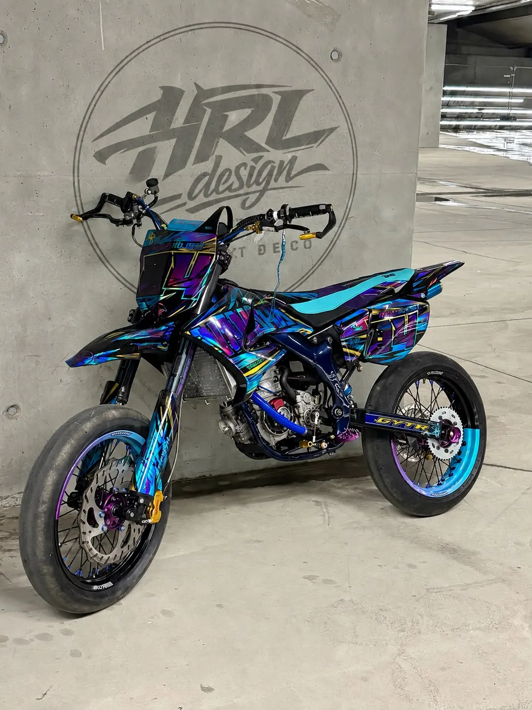 Supermotard violet et turquoise devant le logo HRL Design