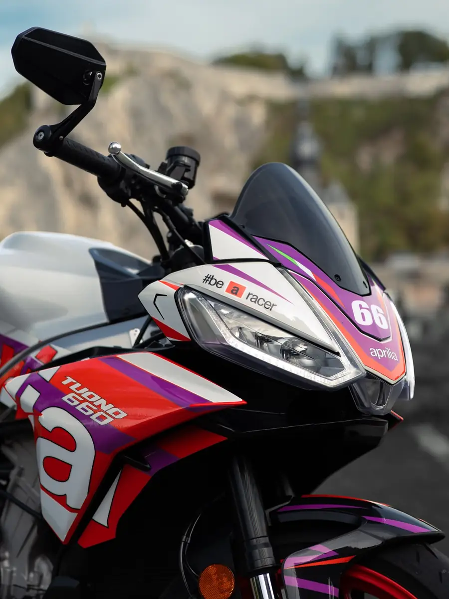 Gros plan sur le carénage avant et le phare d’une Aprilia Tuono 660 avec kit déco HRL numéro 66